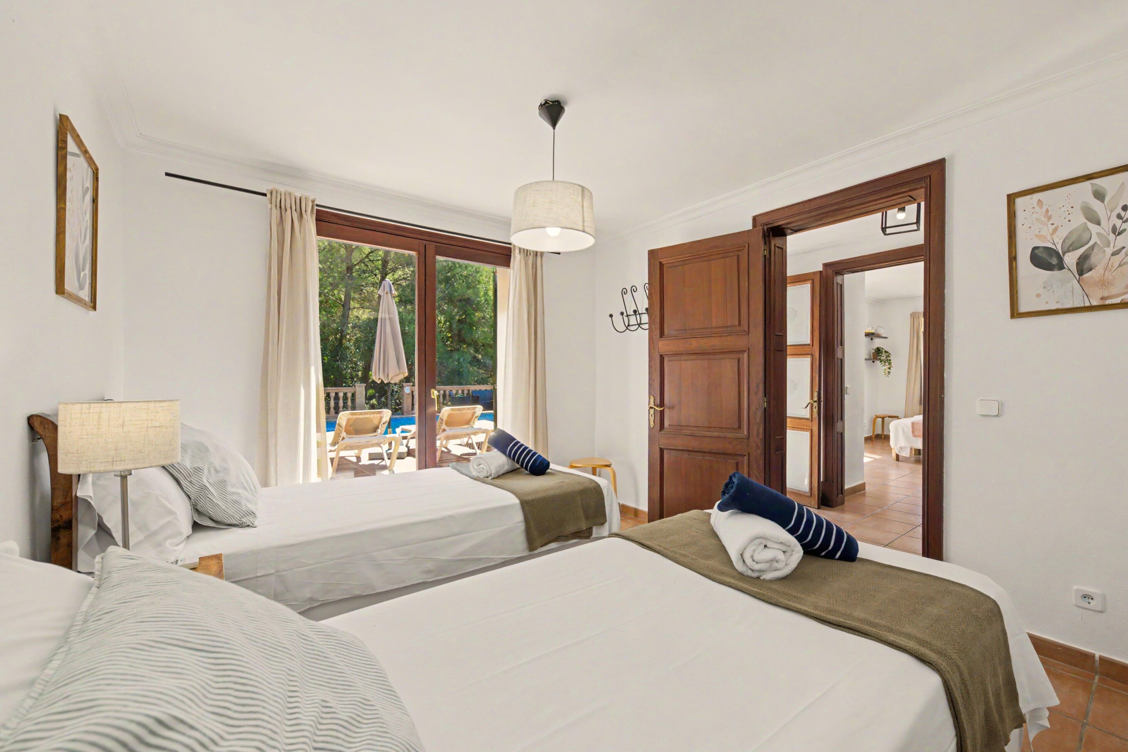 A hotel room with two beds, a view of the outdoors, and a door leading to a balcony.