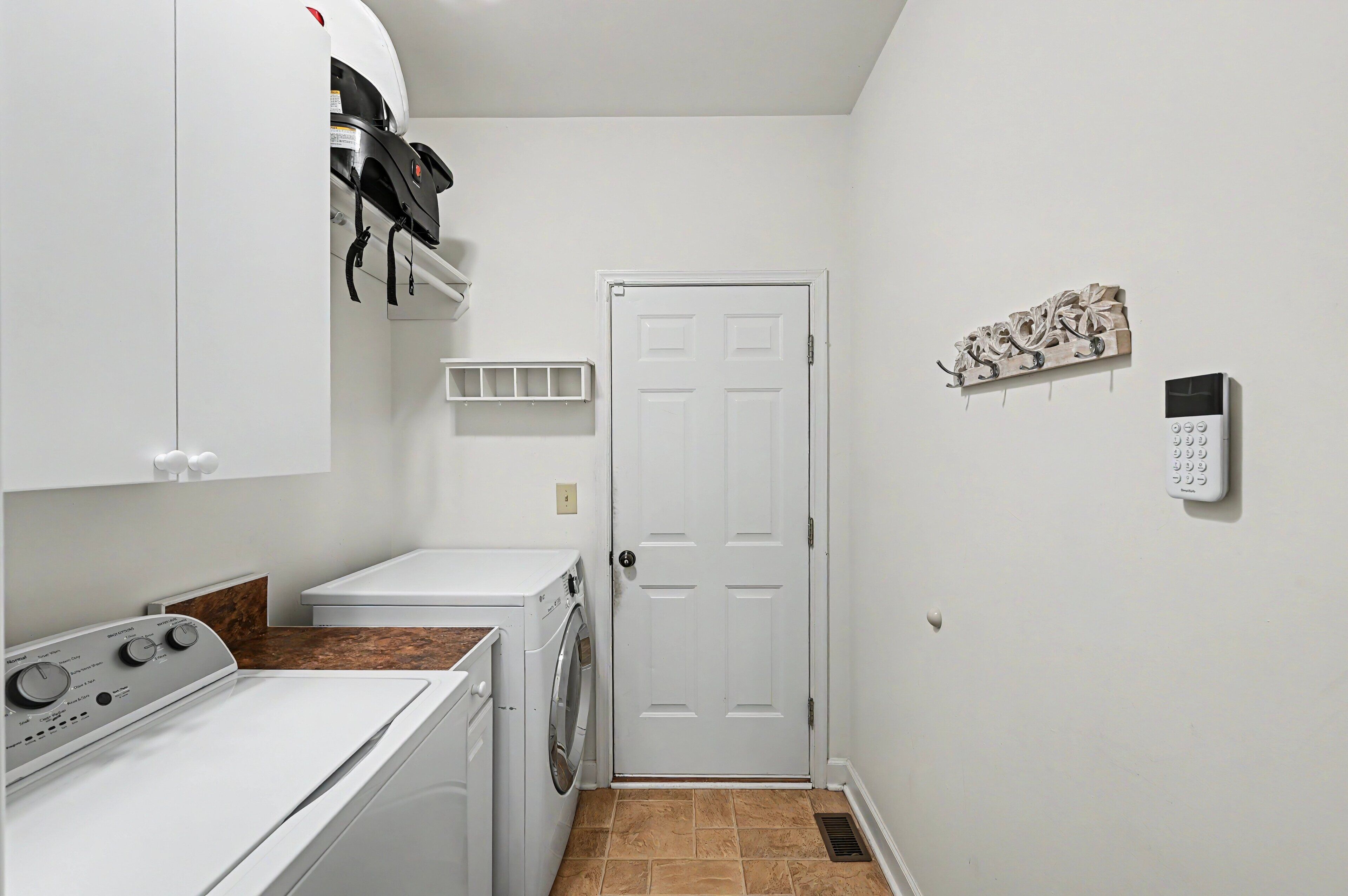 A laundry room with a washing machine, dryer, and a door with a keypad lock.
