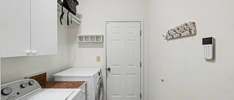 A laundry room with a washing machine, dryer, and a door with a keypad lock.