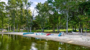 Un parco sul lago con alberi, una spiaggia di sabbia e una zona picnic.