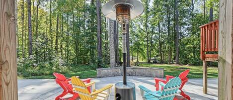 An outdoor seating area with Adirondack chairs and a wood-burning stove.