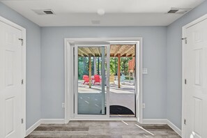 A room with a large sliding glass door leading to an outdoor area with chairs and a covered seating area. - Lakefront Dog Friendly with boat mooring, deck, hot tub, game room & fast WiFi (Bumpass)
