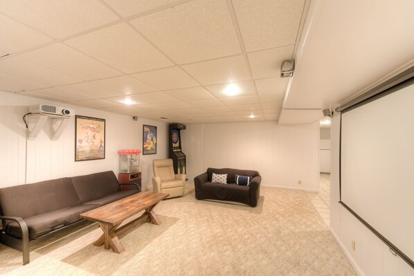 A room with a brown sofa, a wooden coffee table, a beige armchair, and a black couch with patterned pillows. - Three-story dog-friendly home with large deck, wood swing, firepit, lawn, & more (Mineral)