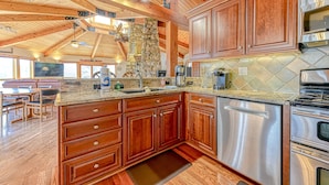 A spacious kitchen with wooden cabinets, stainless steel appliances, and a stone accent wall. - Huge lakefront home with A/C, sunroom, WIFI,game room, deck, & kayaks (Louisa)