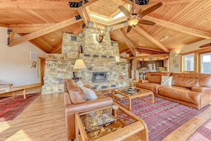 A spacious living area with a stone fireplace, leather sofas, and a wooden ceiling. - Huge lakefront home with A/C, sunroom, boat ramp, WIFI,game room, deck, & kayaks (Louisa)