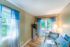 A room with a bed, a TV, a bookshelf, and a window with curtains. - Spacious lake lodge with a private dock, wraparound decks & foosball (Mineral)