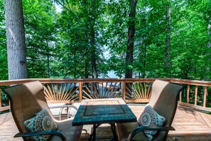 A wooden deck with two chairs and a table, overlooking a forested area. - Spacious lake lodge with a private dock, wraparound decks & foosball (Mineral)