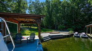 A covered deck with chairs and a ladder, a dock, and a small pond.