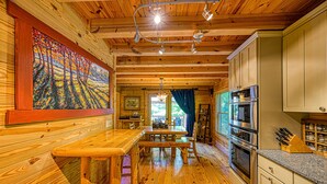 A wooden interior with a dining area, kitchen, and artwork.