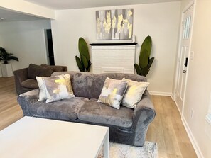 A living room with a grey sofa, white coffee table, and a fireplace. - Comfy Home, 15 mins from Airport & Downtown (Atlanta)