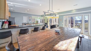 Una cocina moderna con una isla de madera, sillas negras y un amplio ventanal con vistas a una terraza.
