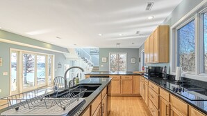 Una cocina moderna con armarios de madera, encimera negra y un amplio ventanal con vistas al exterior.
