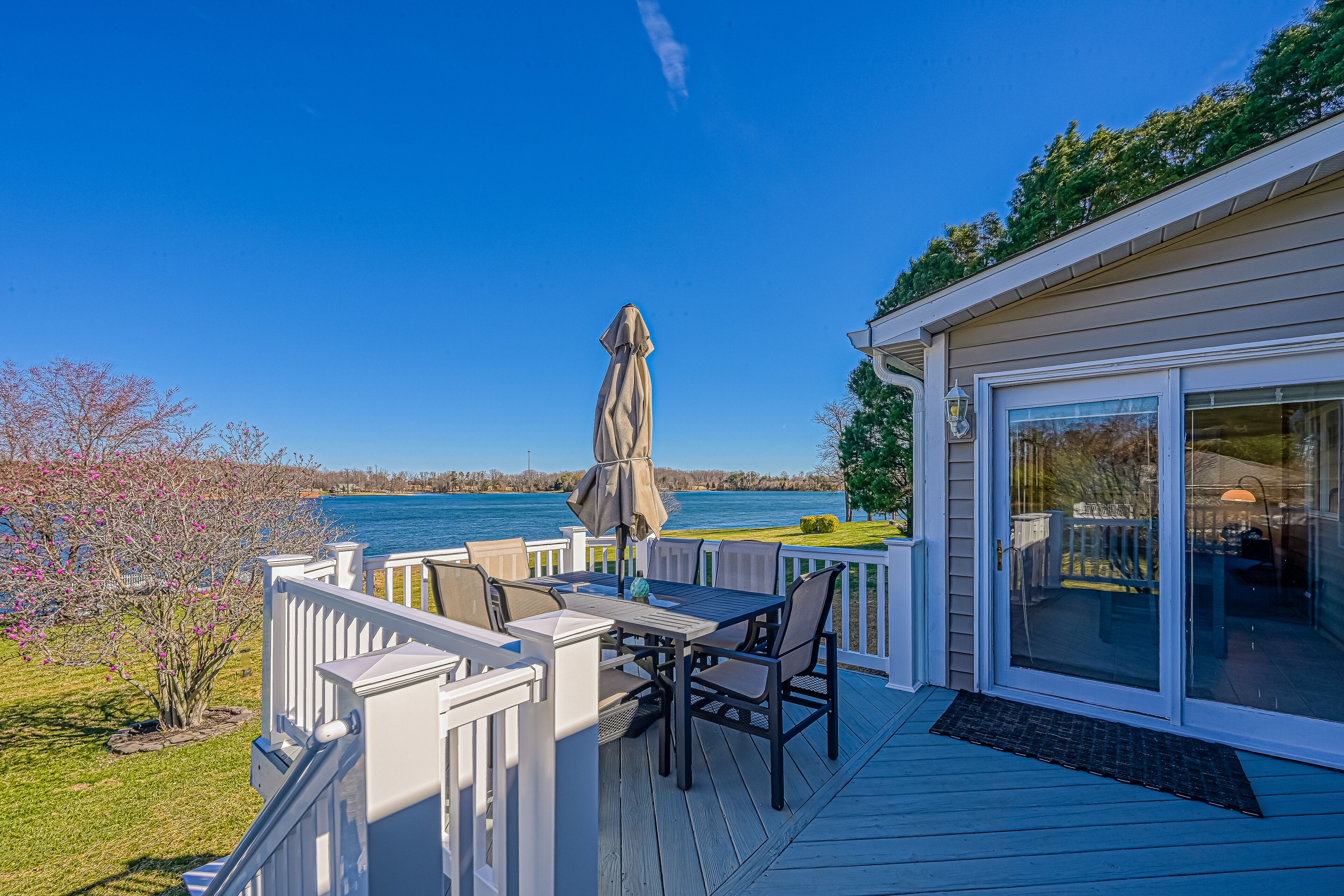 A deck with a table and chairs, overlooking a lake.
