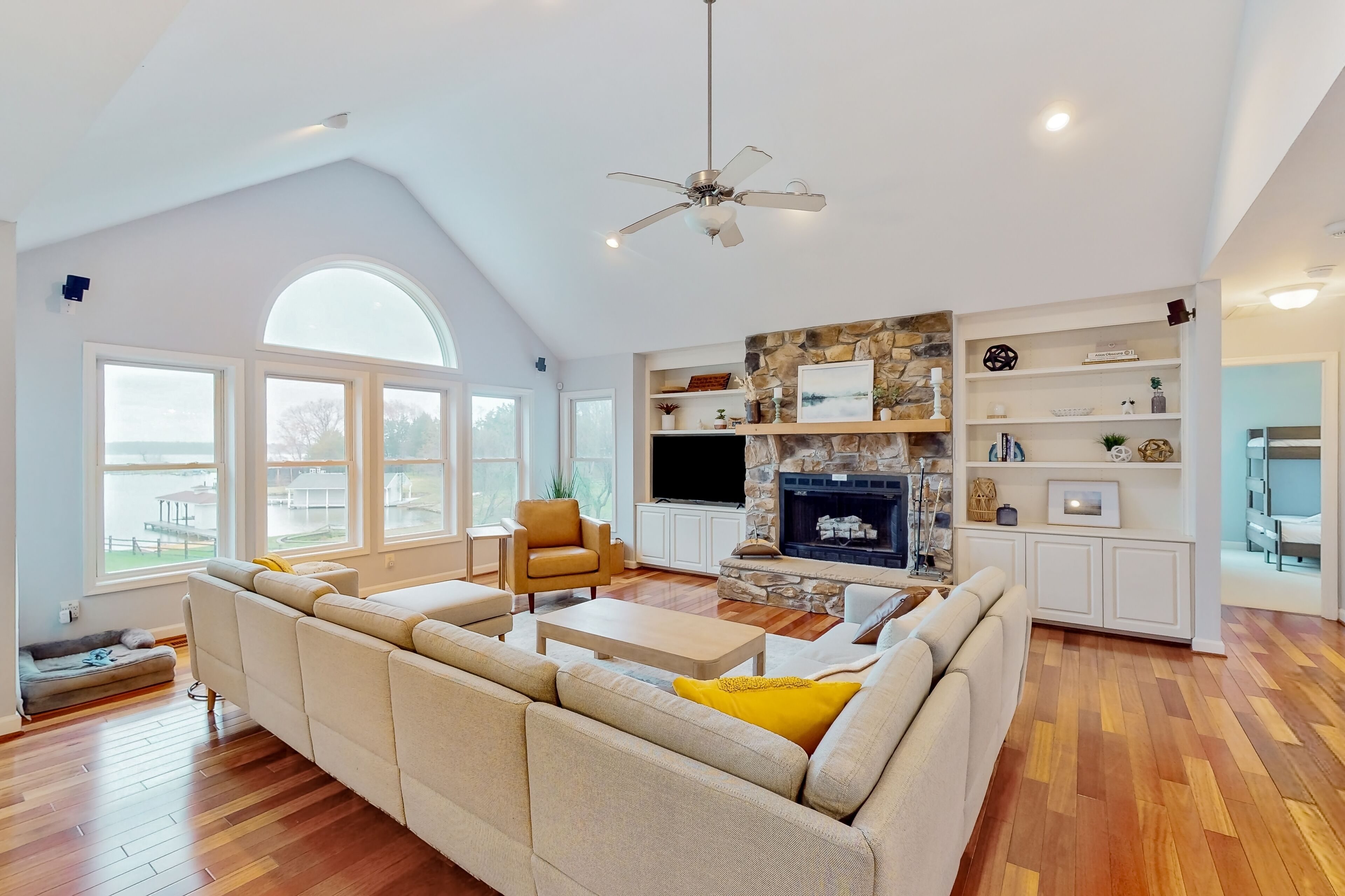 A spacious living room with a large sofa, a coffee table, a fireplace, and a stone accent wall.