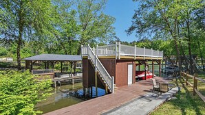 Een houten terras met een klein gebouw, een trap en een steiger.