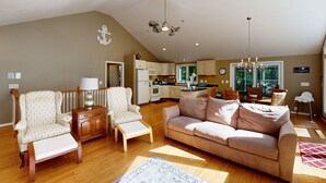 A spacious living room with a sofa, armchairs, and a wooden coffee table. A kitchen is visible in the background with modern appliances. - Pet Friendly, pool table, ping pong, fire pit, free WIFI (Bumpass)