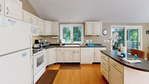 A modern kitchen with white cabinets, a built-in oven, microwave, and dishwasher. There is a window with a view of trees, and a clock on the wall. - Pet Friendly, pool table, ping pong, fire pit, free WIFI (Bumpass)