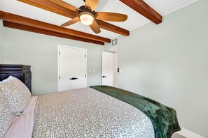 A bedroom with a bed, a ceiling fan, wooden beams, and white doors. - Blue Lagoon 3BR Pool Home Near the Beach (Redington Beach)