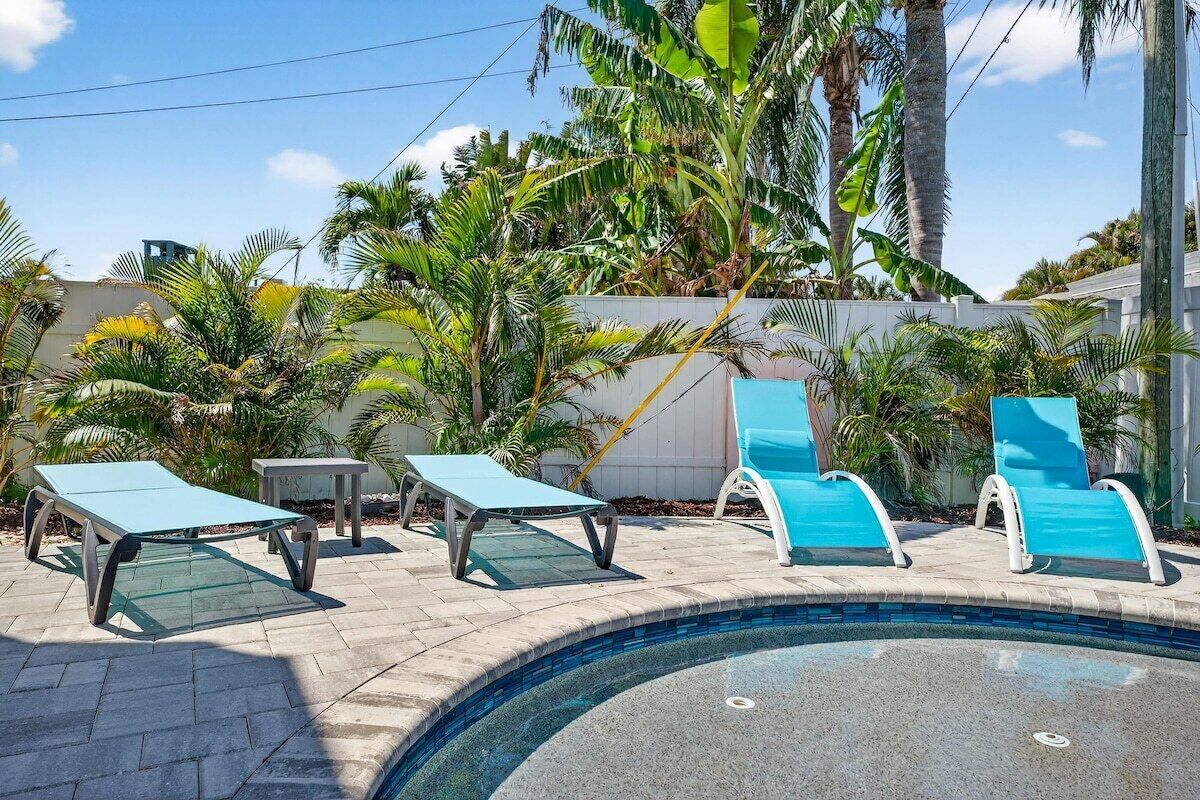 A swimming pool with lounge chairs and palm trees.