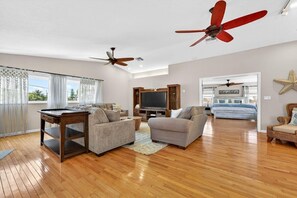 A spacious living room with hardwood flooring, two sofas, a coffee table, and ceiling fans. - Blue Lagoon 3BR Pool Home Near the Beach (Redington Beach)