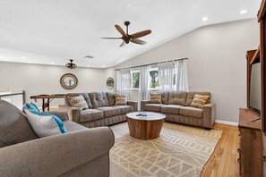 Ein geräumiges Wohnzimmer mit zwei Sofas, einem Couchtisch und einem Deckenventilator.