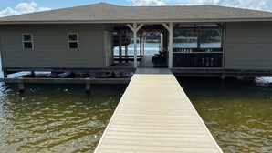 Un muelle de madera que conduce a una estructura cubierta con vista a un cuerpo de agua.