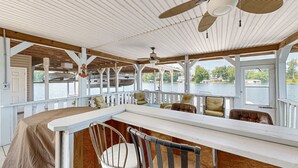 Un espacio de estar al aire libre cubierto con bar, techo de madera y vista al agua.
