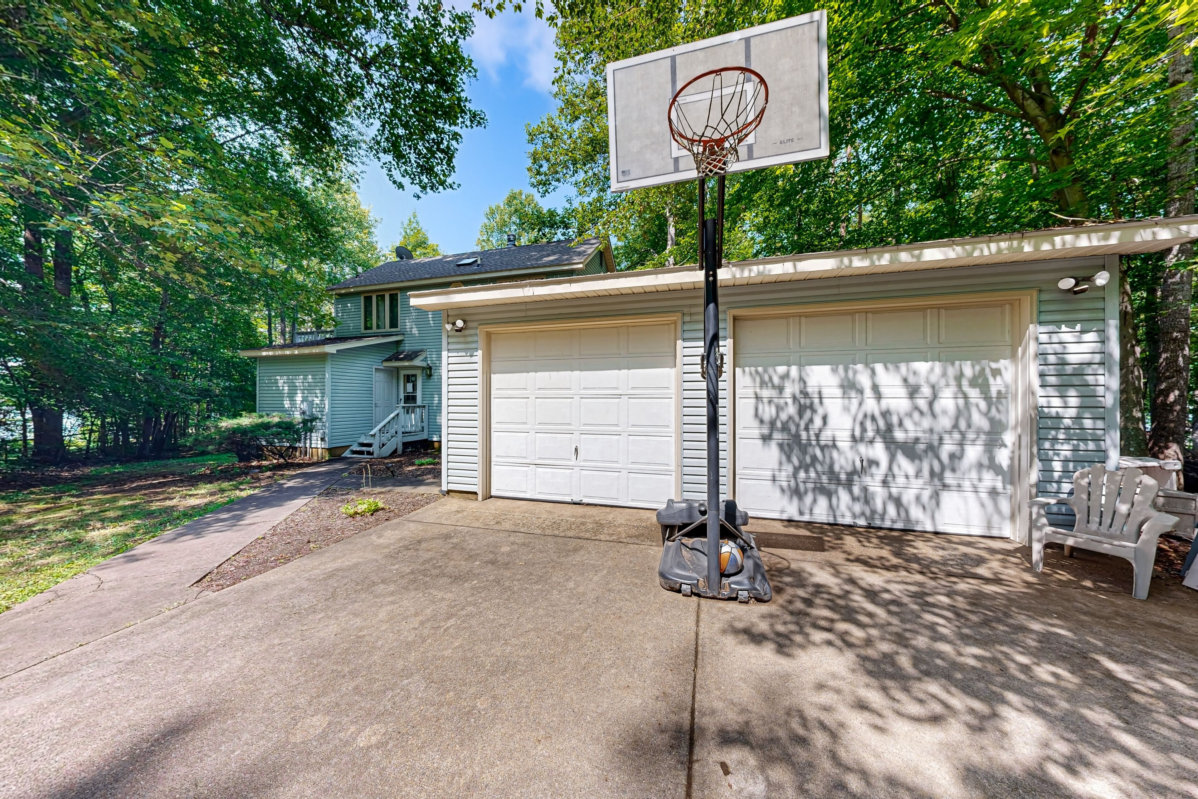 Eine Wohngarage mit Basketballkorb, einer überdachten Auffahrt und einem Haus mit Garagentor.