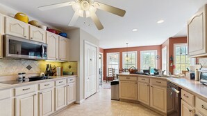 A spacious kitchen with light-colored cabinetry, a large microwave, and a ceiling fan. - Tranquil lakefront retreat with hot tub, screened porch, kayaks, and more (Bumpass)