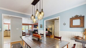 A dining area with a large wooden table, several chairs, and hanging pendant lights. - Tranquil lakefront retreat with hot tub, screened porch, kayaks, and more (Bumpass)