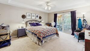 A bedroom with a bed, a nightstand, a dresser, a chair, a ceiling fan, and a view of the outdoors through a sliding glass door. - Tranquil lakefront retreat with hot tub, screened porch, kayaks, and more (Bumpass)