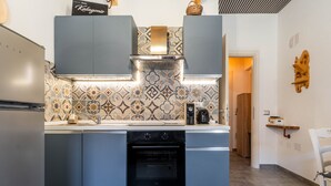 Una cocina moderna con horno empotrado, armarios de acero inoxidable y azulejos decorativos en la trasera.
