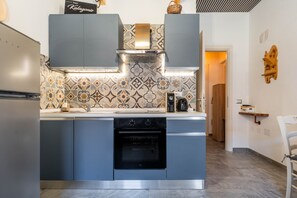 Una cucina moderna con forno integrato, pensili in acciaio inossidabile e piastrelle decorate per la parete di fondo.
