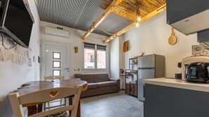 Una cocina moderna con comedor, un sofá y un televisor montado en la pared.