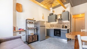 Una cocina compacta con electrodomésticos modernos, un comedor con mesa de madera y una zona de estar acogedora.