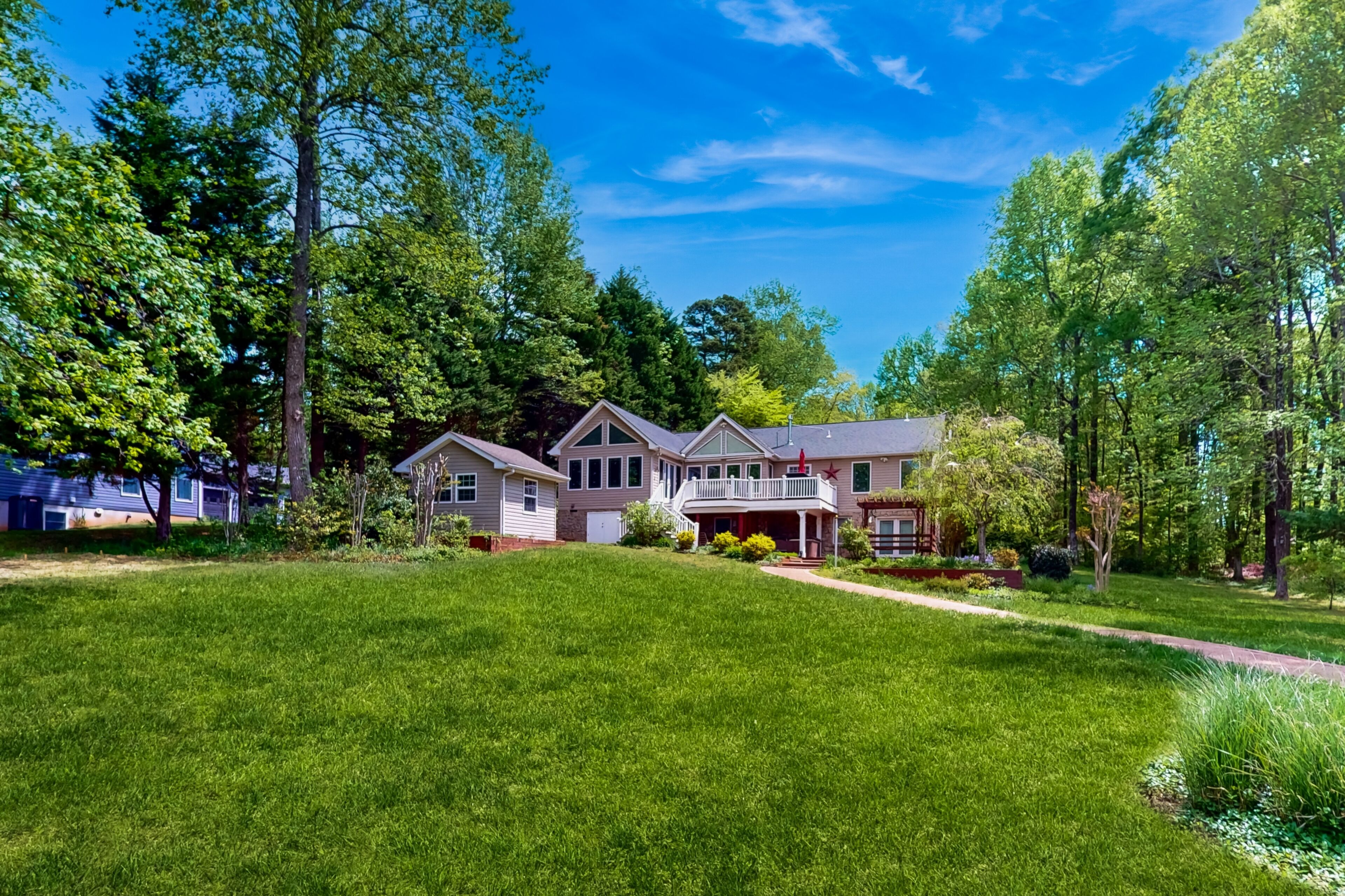 A large, two-story house with a spacious front yard, surrounded by tall trees and a well-maintained lawn.