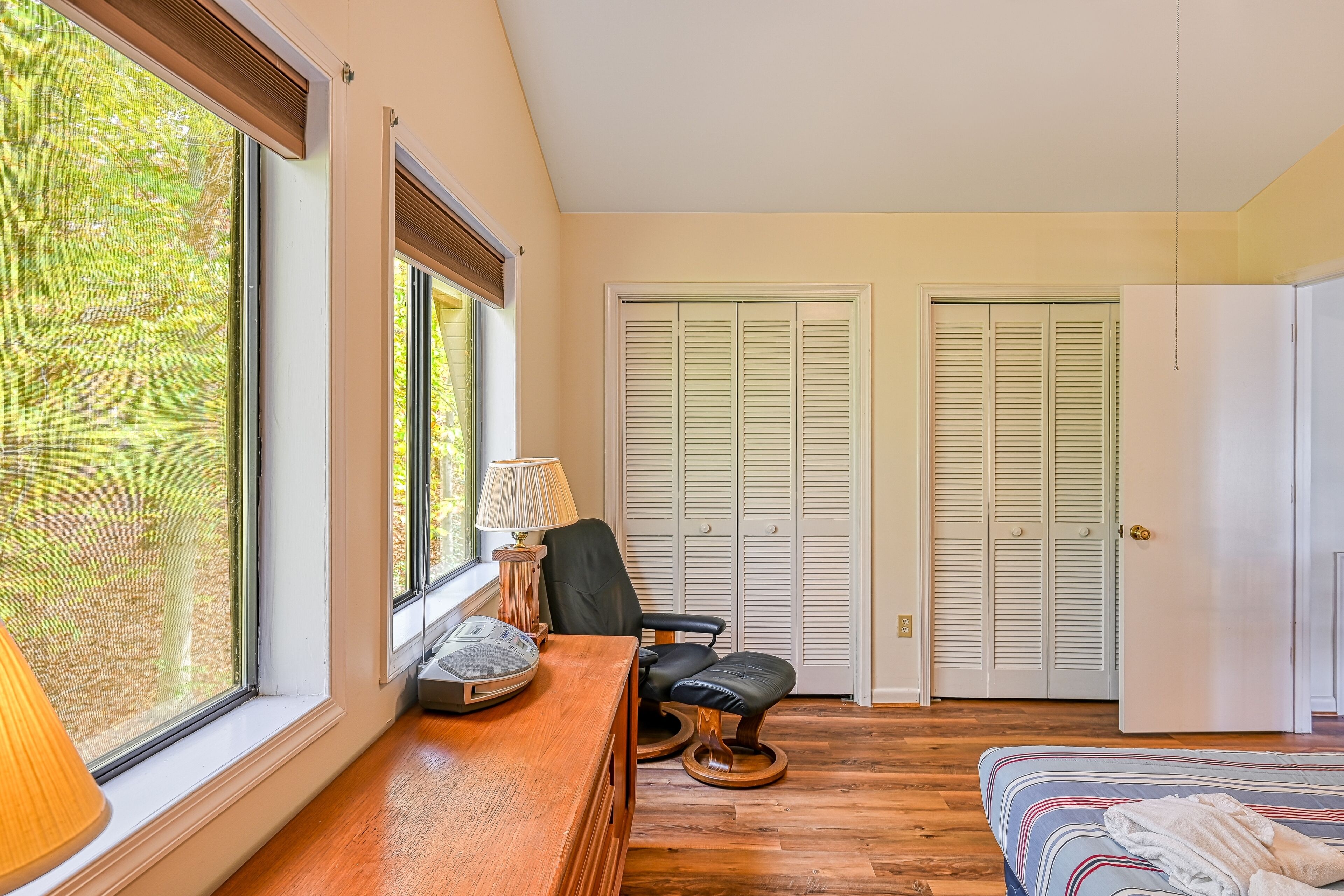 A bedroom with a wooden desk, a chair, a bed, and two closets.
