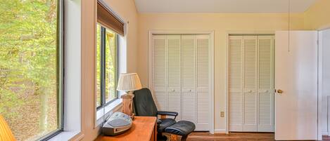 A bedroom with a wooden desk, a chair, a bed, and two closets.