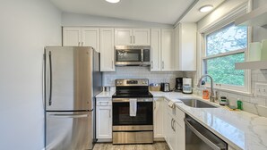 Una cocina moderna con electrodomésticos de acero inoxidable, gabinetes blancos y un amplio ventanal que proporciona luz natural.