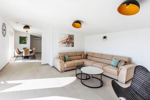 Ein modernes Wohnzimmer mit einer Eckcouch, einem runden Couchtisch und Pendelleuchten.
