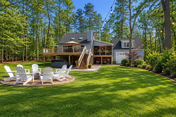A two-story house with a deck, outdoor seating, and a fire pit.
