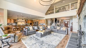 Tilava olohuone, jossa on suuri kulmasohva, nahkainen nojatuoli ja takka.