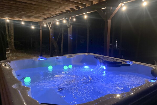 Ein Whirlpool mit blauer Beleuchtung und einer Holz-Pergola.