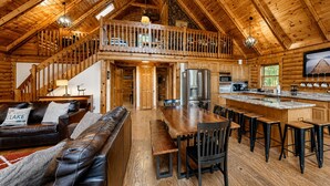Una cabaña de madera espaciosa con un dormitorio en entrepiso, comedor y cocina.