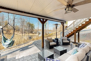 A covered patio with outdoor furniture, a hammock, and a view of the surrounding landscape.