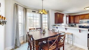 Una cocina con armarios de madera, una isla central y una zona de comedor con sillas.