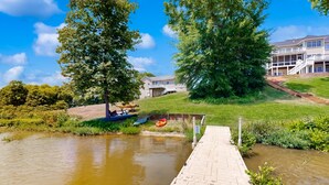 Un quai au bord de la rivière, avec une passerelle en bois menant à une maison dotée d’un balcon.