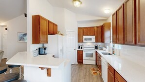 Une cuisine moderne avec des meubles en bois, un plan de travail blanc et un four à micro-ondes encastré.