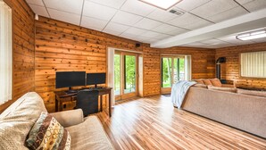 L’intérieur d’une cabane en rondins, avec un plancher en bois, un canapé, un téléviseur et une cheminée.