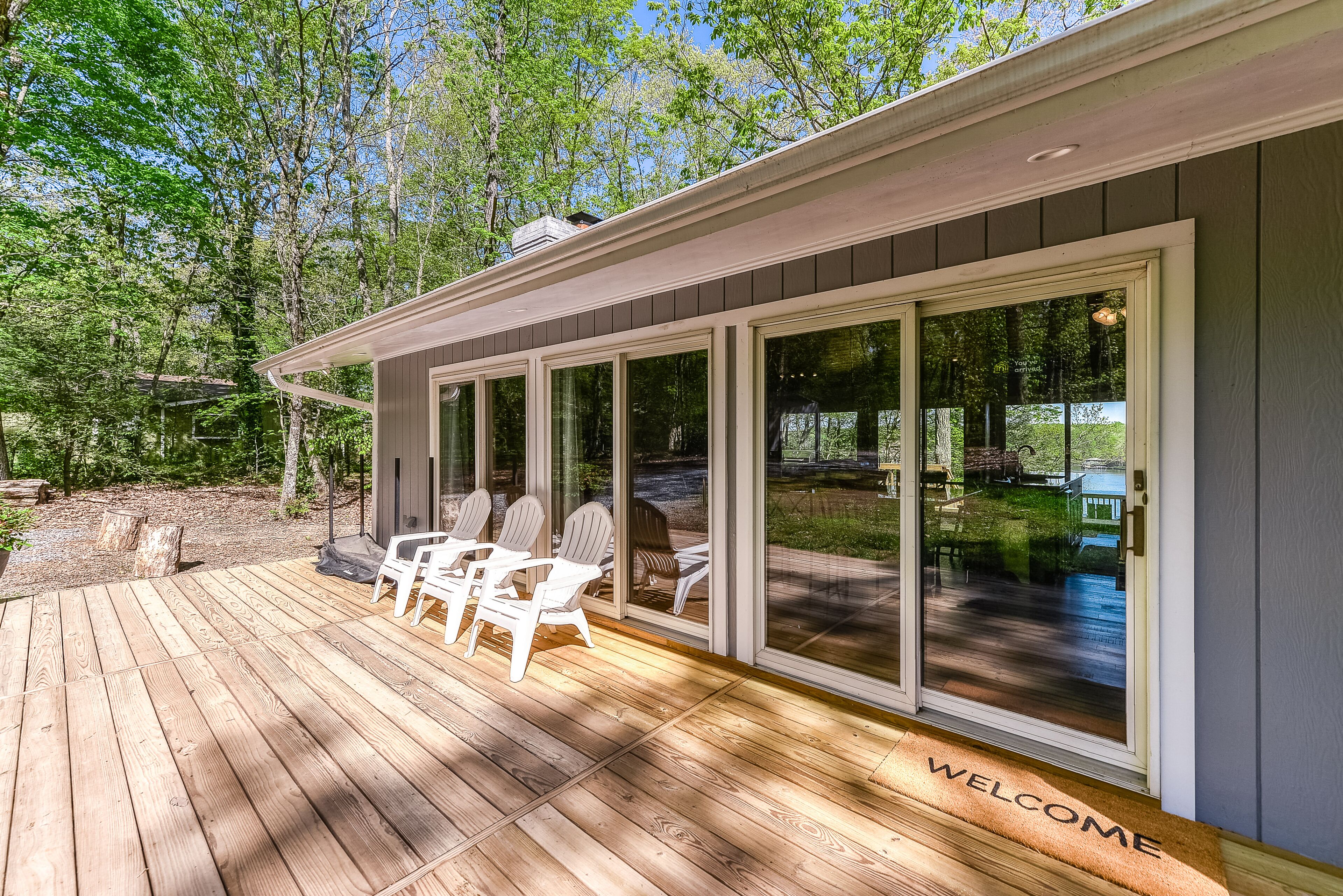 Una terraza de madera con mobiliario exterior y un portón corredizo que da a un porche cubierto.